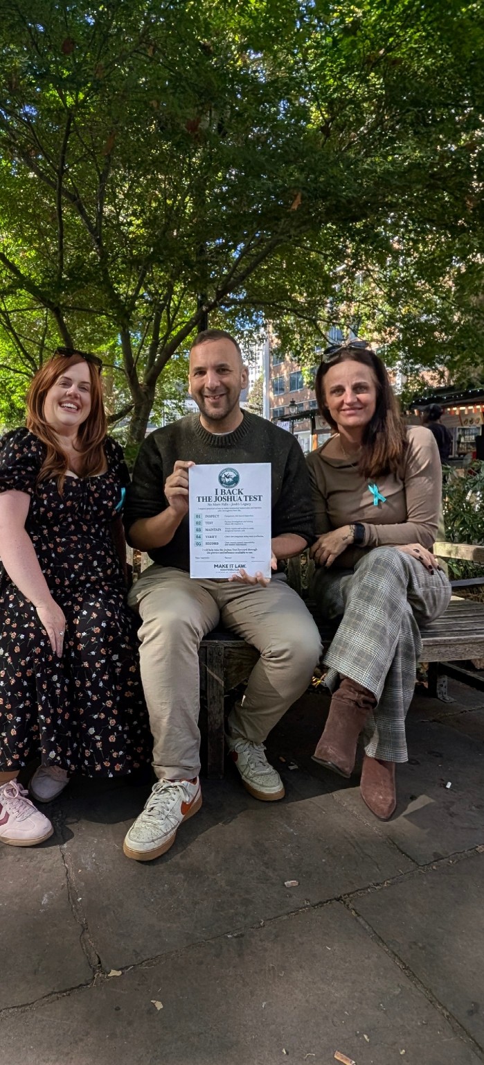 Three campaign participants seated together in Holborn, with one holding The Joshua Test campaign pledge