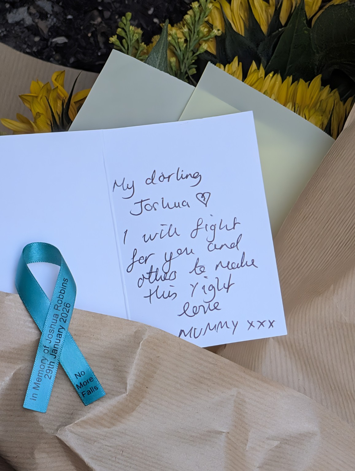 Sunflowers, a handwritten card to Joshua and a teal No More Falls memorial ribbon